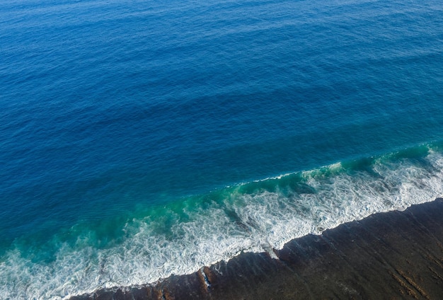 Vue aérienne d'un océan bleu serein avec des vagues douces s'approchant de la côte