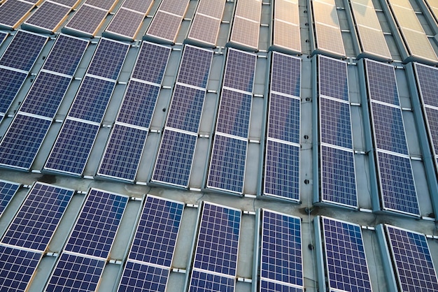 Vue aérienne de panneaux solaires photovoltaïques bleus montés sur le toit d'un bâtiment industriel pour produire de l'électricité écologique verte Production d'un concept d'énergie durable