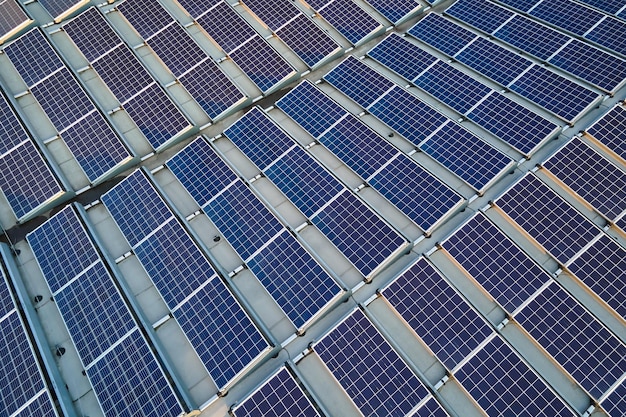 Vue aérienne de panneaux solaires photovoltaïques bleus montés sur le toit d'un bâtiment industriel pour produire de l'électricité écologique verte Production d'un concept d'énergie durable