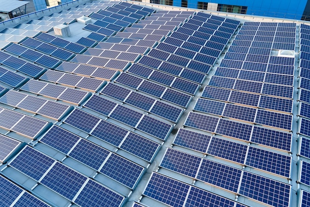 Vue aérienne de panneaux solaires photovoltaïques bleus montés sur le toit d'un bâtiment industriel pour produire de l'électricité écologique verte Production d'un concept d'énergie durable