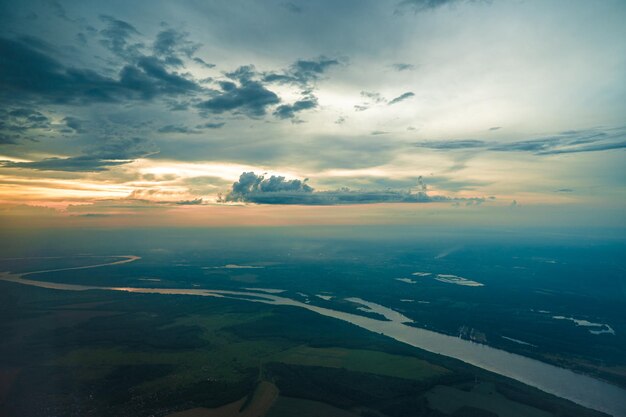 Vue aérienne panoramique vue paysage depuis la fenêtre de l'avion Avion de ligne volant dans un ciel nuageux haut avion vole dans le ciel bleu avec des nuages multicolores au coucher du soleil Fond de voyage