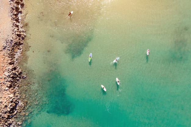 Vue aérienne par drone de personnes pratiquant le Stand Up Paddle ou SUP en mer turquoise turquoise.