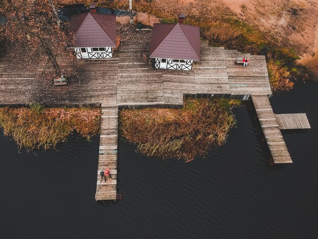 Vue aérienne d'un pêcheur avec une canne à pêche sur la jetée, la rive du lac, la forêt en automne. Finlande.