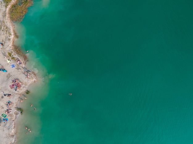 Vue aérienne de personnes nageant dans l'eau bleu azur bronzer au repos à l'espace de copie de plage de sable juste au-dessus