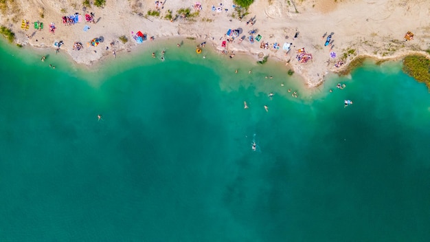 Vue aérienne de personnes nageant dans l'eau bleu azur se faisant bronzer au repos sur la plage de sable copie espace directement au-dessus