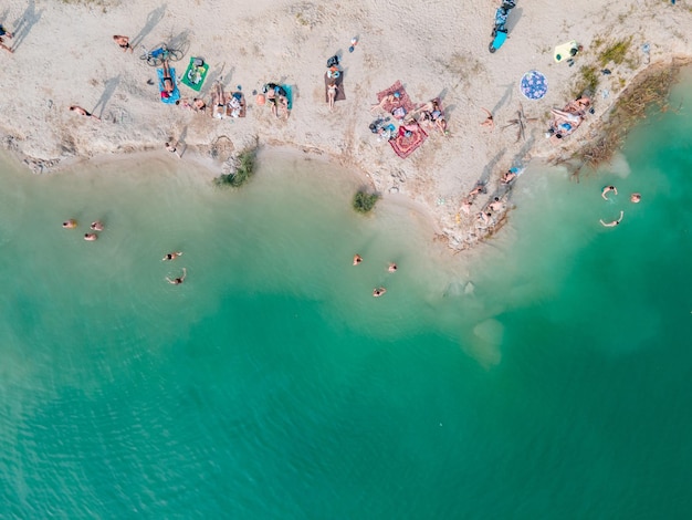 Vue aérienne de personnes nageant dans l'eau bleu azur se faisant bronzer au repos sur la plage de sable copie espace directement au-dessus