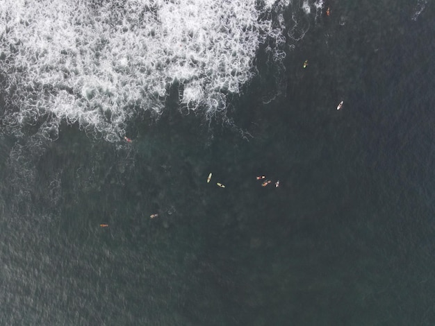 Vue aérienne de personnes surfant sur les vagues avec des planches de surf en vacances à Bali Indonésie