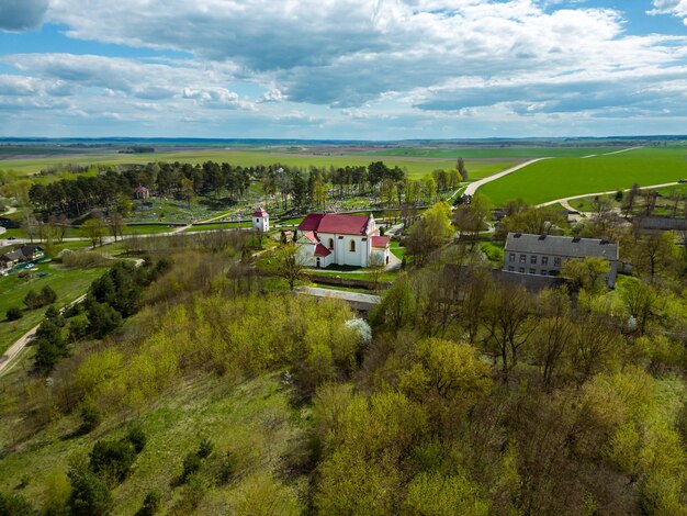 Vue aérienne d'un petit village près d'une route de terre De grands champs multicolores plantés de diverses cultures agricoles Champ de blé vue d'oiseau