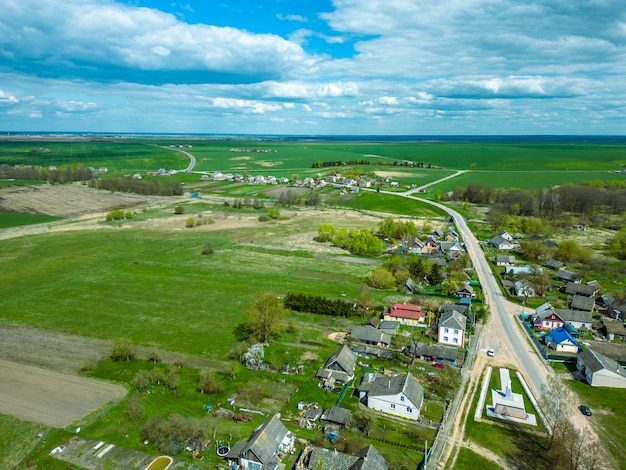 Vue aérienne d'un petit village près d'une route de terre De grands champs multicolores plantés de diverses cultures agricoles Champ de blé vue d'oiseau