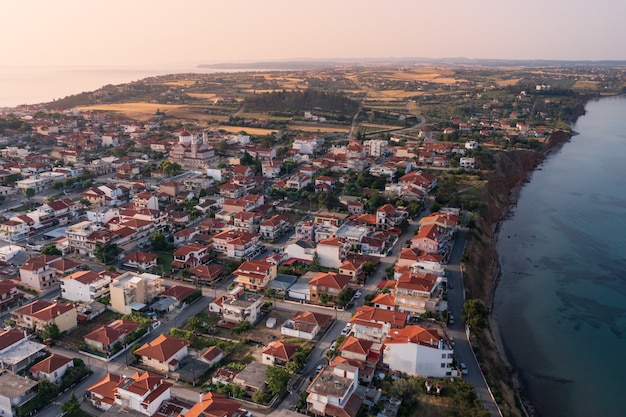 Vue aérienne d'une petite ville aux maisons blanchies à la chaux sous des toits rouges se tenant sur une étroite bande de terre à la base d'une péninsule au lever du soleil