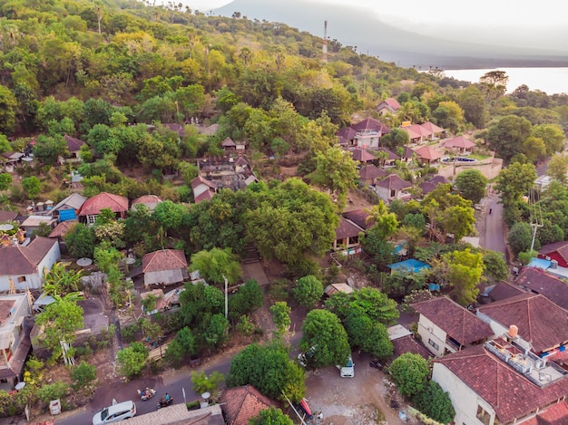 Vue aérienne de la plage d'Amed à Bali Indonésie Bateaux de pêche traditionnels appelés jukung sur la plage de sable noir et le volcan du mont Agung en arrière-plan partiellement recouvert de nuages