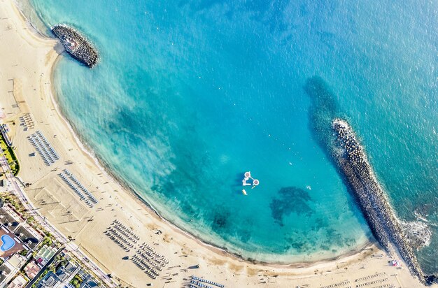 Photo vue aérienne de la plage de la baie de los cristianos à tenerife avec des transats et des parasols miniatures