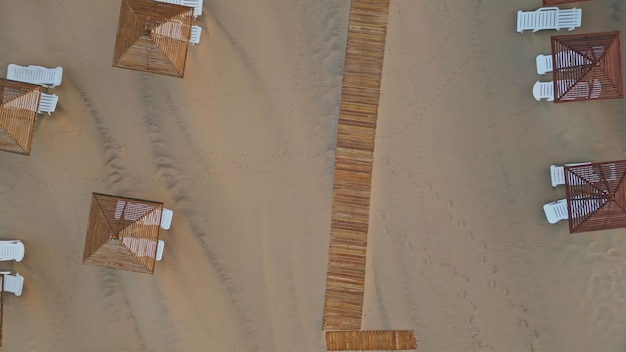 Vue aérienne de la plage de la station balnéaire en été. Parapluies en osier, fauteuils longs.