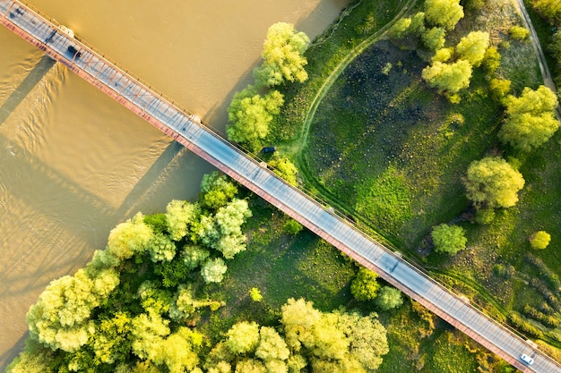 Photo vue aérienne d'un pont routier étroit qui s'étend sur une large rivière boueuse