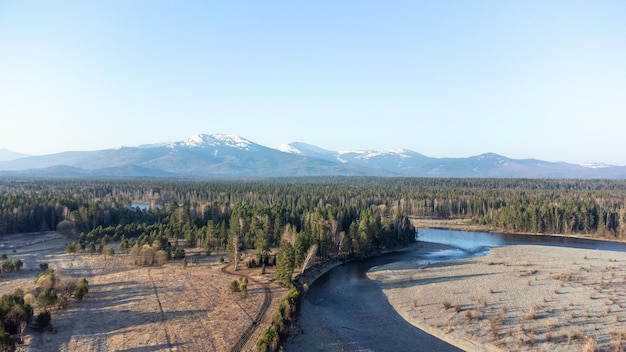 Vue aérienne de la rivière de montagne dans la forêt de la taïga au début du printemps au coucher du soleil Paysage sibérien ou canadien d'en haut