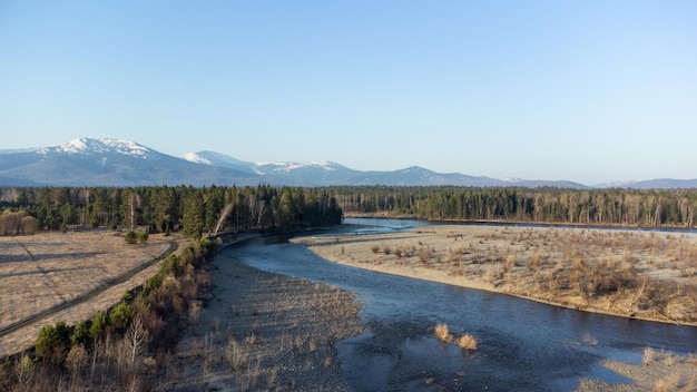 Vue aérienne de la rivière de montagne dans la forêt de la taïga au début du printemps au coucher du soleil Paysage sibérien ou canadien d'en haut