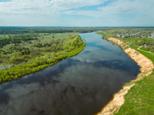 Vue aérienne de la rivière sinueuse et des champs en fleurs La rivière coule le long des champs agricoles et des forêts Voler un drone au-dessus des champs forêts et rivières Paysage naturel