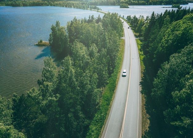 Vue aérienne de la route de campagne à travers les bois verts et les lacs bleus en Finlande