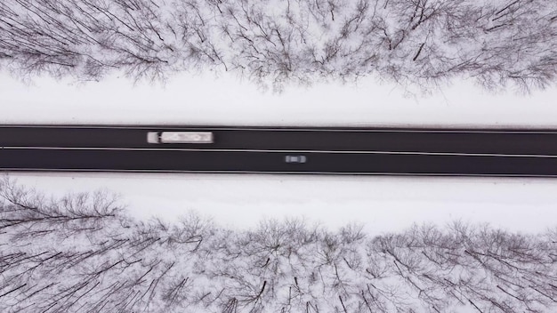 Vue aérienne de la route d'hiver et de la forêt avec des arbres couverts de neige