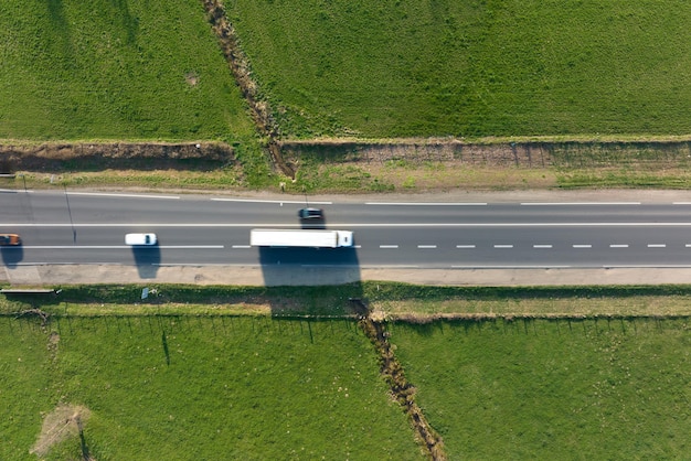 Vue aérienne de la route interurbaine entre les champs agricoles verdoyants avec des voitures à conduite rapide Vue de dessus depuis le drone du trafic routier