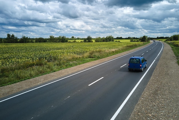 Vue aérienne de la route interurbaine entre les champs agricoles verdoyants avec des voitures à conduite rapide Vue de dessus depuis le drone du trafic routier