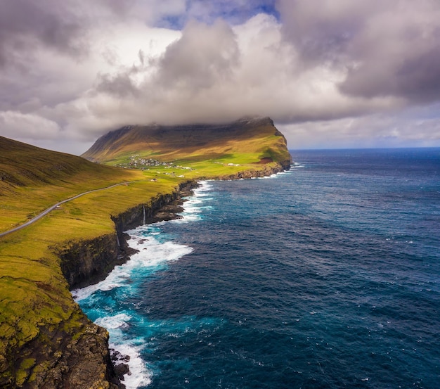 Vue aérienne d'une route longeant la côte jusqu'à un village des îles Féroé