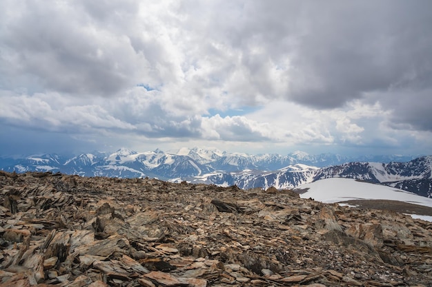 Vue aérienne spectaculaire sur une grande chaîne de montagnes enneigées sous un ciel nuageux pluvieux changeant Paysage alpin atmosphérique lumineux avec un haut sommet de montagne enneigé dans des nuages bas