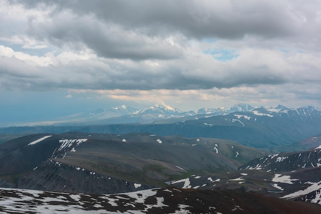 Vue aérienne spectaculaire sur le sommet d'une haute montagne enneigée au soleil dans un ciel couvert Paysage de montagne atmosphérique à haute altitude avec nébulosité Vue imprenable sur le sommet d'une montagne enneigée à la lumière sous un ciel nuageux