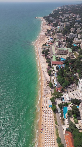 Vue aérienne de la station balnéaire de Golden Sands en Bulgarie pendant la saison estivale, une gamme d'hôtels, des piscines et des foules de gens appréciant la mer.