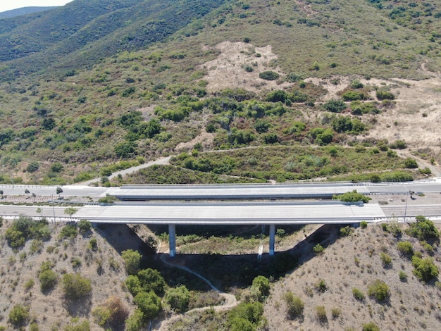 Vue aérienne des supports du viaduc du pont routier dans la vallée parmi les collines jaunes sèches