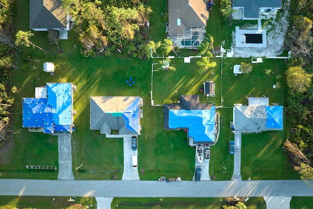 Vue aérienne des toits des maisons endommagées par l'ouragan Ian recouvertes d'une bâche de protection bleue contre les fuites d'eau de pluie jusqu'au remplacement des bardeaux d'asphalte