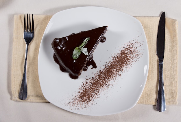 Vue aérienne d'une tranche de délicieux gâteau au chocolat fraîchement cuit avec du glaçage dégoulinant sur les côtés servi sur une assiette à table