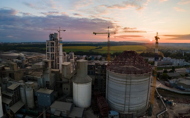 Vue aérienne de l'usine de ciment en construction avec une structure de centrale à béton élevée et des grues à tour dans la zone de production industrielle Fabrication et concept industriel mondial