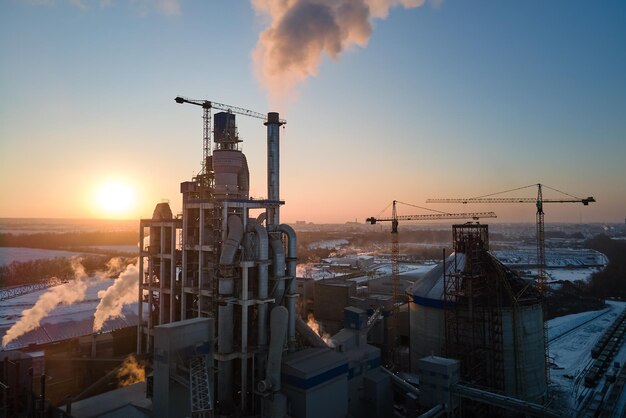 Vue aérienne de l'usine de ciment avec une structure de centrale à béton élevée et une grue à tour dans la zone de production industrielle en soirée Fabrication et concept industriel mondial