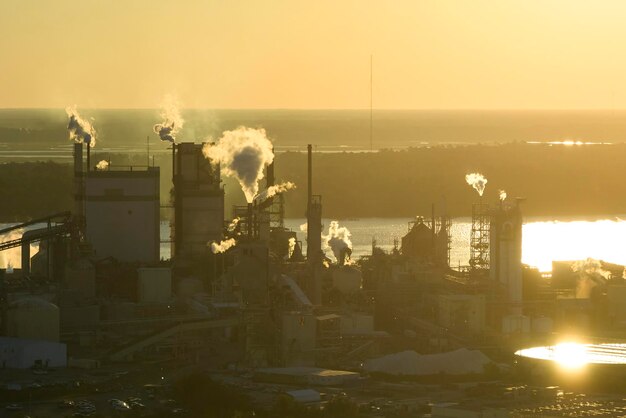 Vue aérienne de l'usine de transformation du bois avec de la fumée provenant du processus de production polluant l'atmosphère du chantier de fabrication de l'usine Site industriel au coucher du soleil