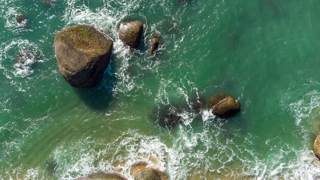 Vue aérienne de vagues douces frappant les rochers sur une côte de sable de plage brésilienne. Balnéaire Camboriu.