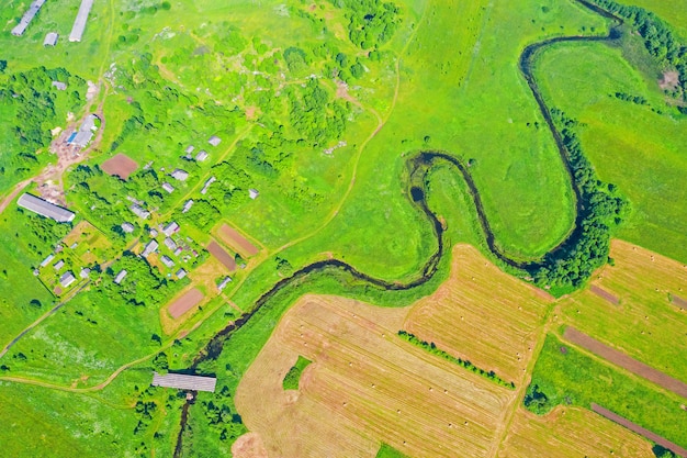 Vue aérienne de la vallée du paysage rural naturel d'une rivière sinueuse parmi les champs verts et les forêts.