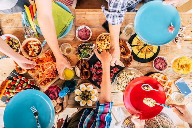 Vue aérienne verticale d'une table pleine de plats et de boissons traditionnels colorés et d'un groupe de générations d'âges mixtes qui s'amusent à célébrer ensemble - concept d'amitié et de fête