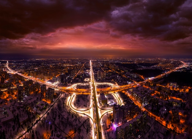 Vue aérienne de la ville de nuit et de l'échangeur de transport éclairé par des lanternes. Ciel nocturne sombre.