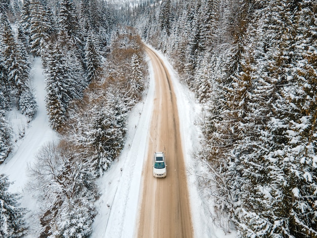 Vue aérienne de la voiture sur la route enneigée en hiver dans les montagnes