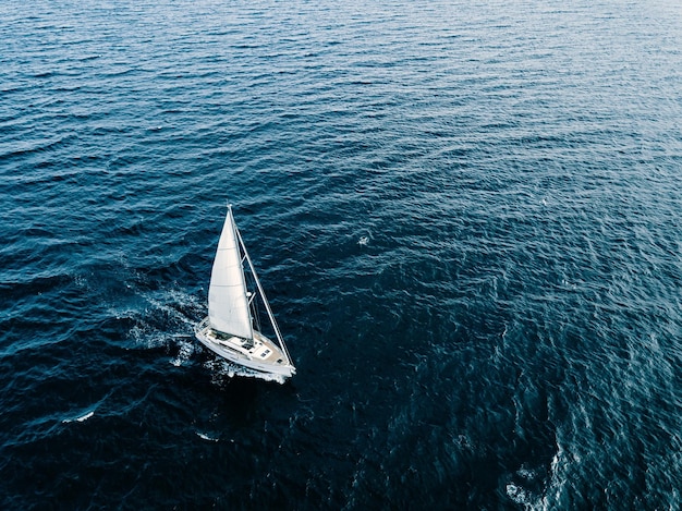 Vue aérienne de yachts à voile avec des voiles blanches dans un état venteux en mer d'un bleu profond