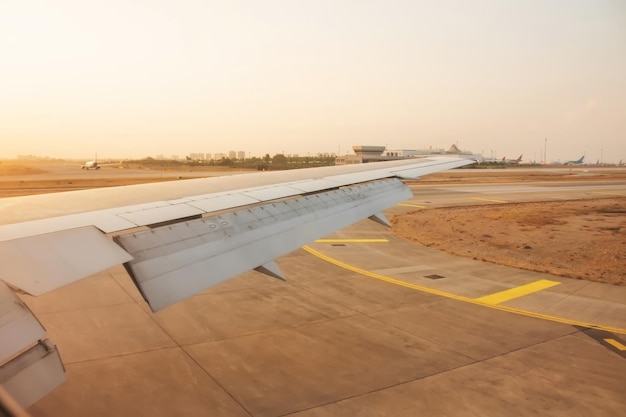 Vue de l'aile depuis la cabine de l'avion après l'atterrissage sur la piste à l'aéroport orange light matin lever du soleil