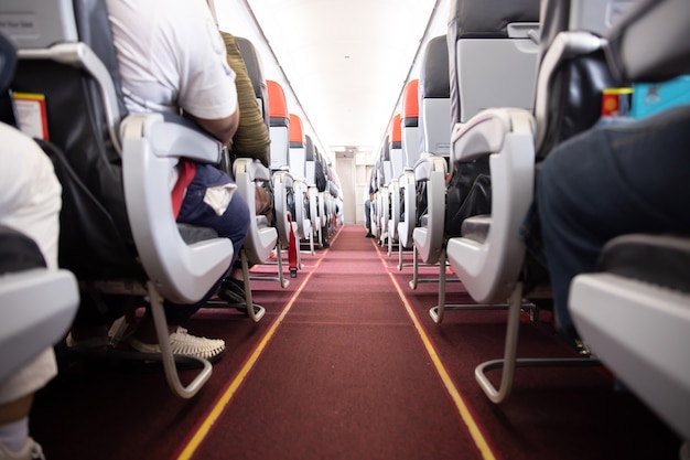 Photo vue de l'allée de l'avion avec les passagers assis sur leurs sièges