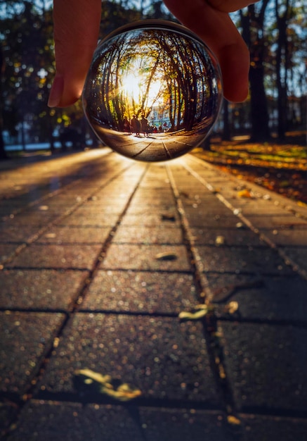 Vue sur l'allée du parc avec les promeneurs et les touristes à travers une boule de verre au coucher du soleil à Stavropol Russie