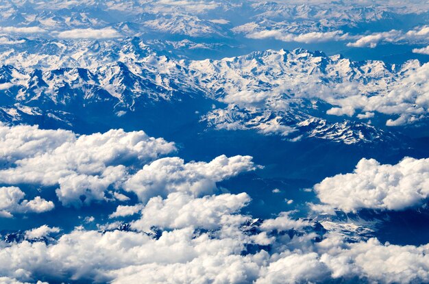 Vue sur les Alpes suisses enneigées depuis les hauteurs au-dessus des nuages blancs.