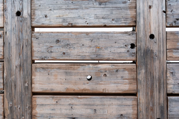 Photo vue de l'ancienne clôture faite de planches de bois massives disposées horizontalement avec des trous ronds disposés au hasard. concept de texture, intérieur