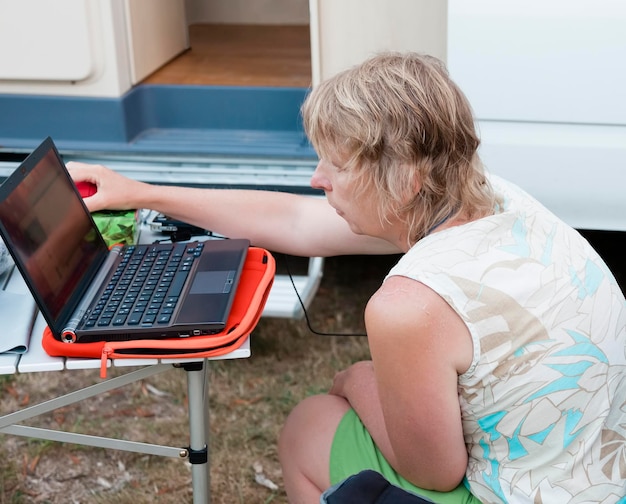 Photo vue angélique haute d'une femme mature utilisant un ordinateur portable à l'extérieur