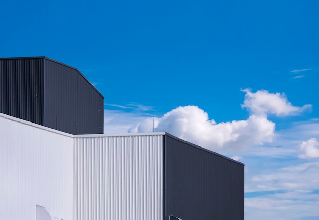 Vue en angle bas des bâtiments d'usine en tôle ondulée noire et blanche sur fond de ciel bleu