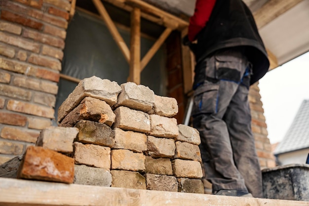 Vue en angle bas du constructeur construisant une maison Mise au point sélective sur un tas de briques