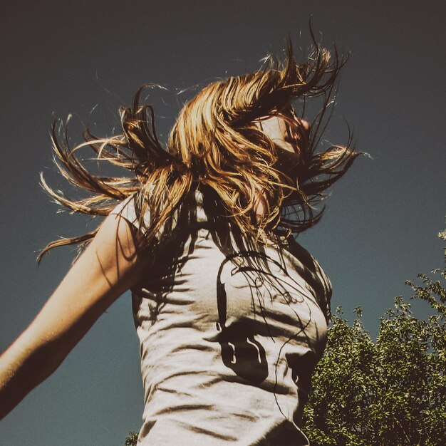 Photo vue à angle bas d'une femme avec les cheveux en désordre contre le ciel